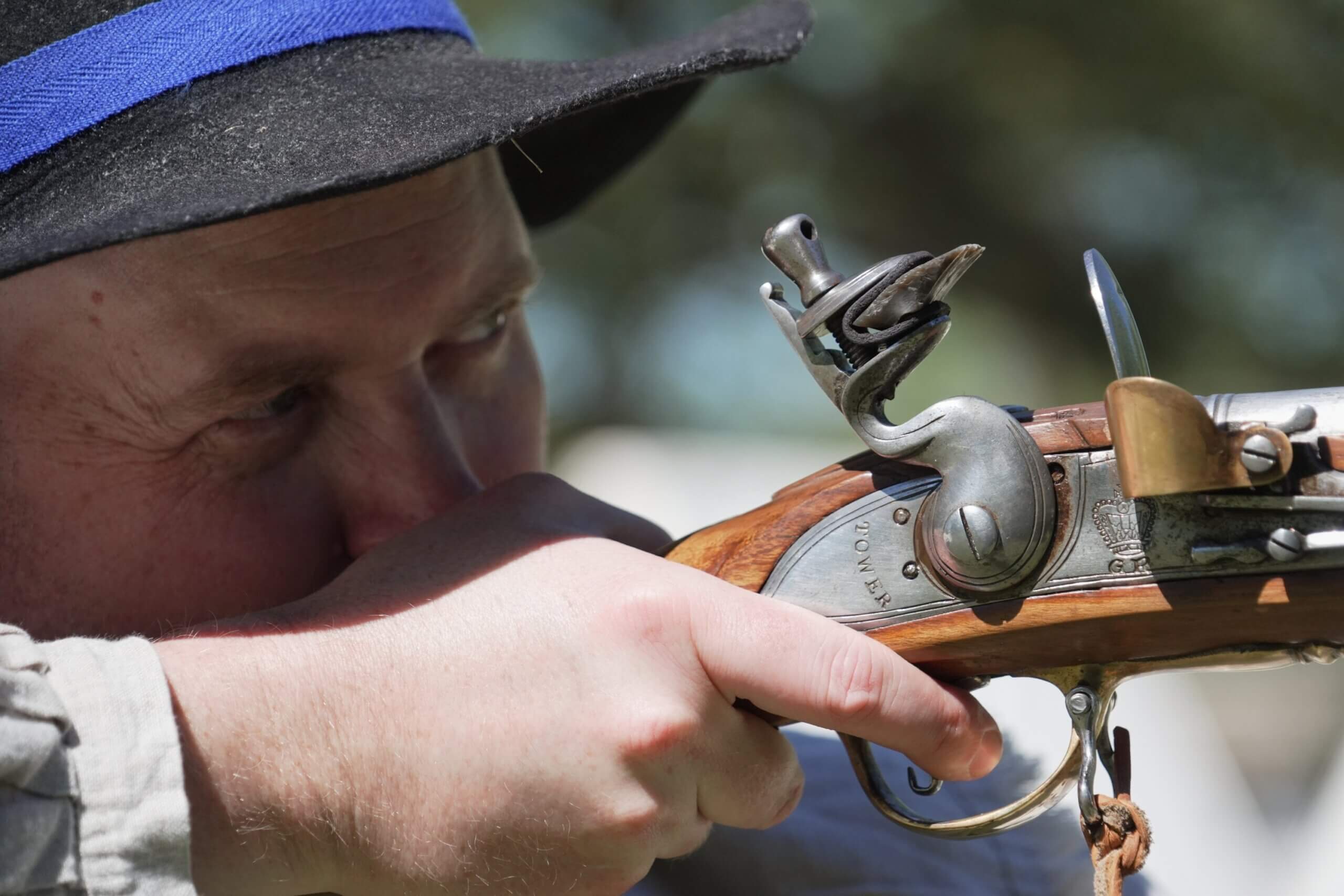 Close-up of a reproduction flintlock musket similar to those used by American revolutionaries in 1776, with polished walnut stock and brass fittings.