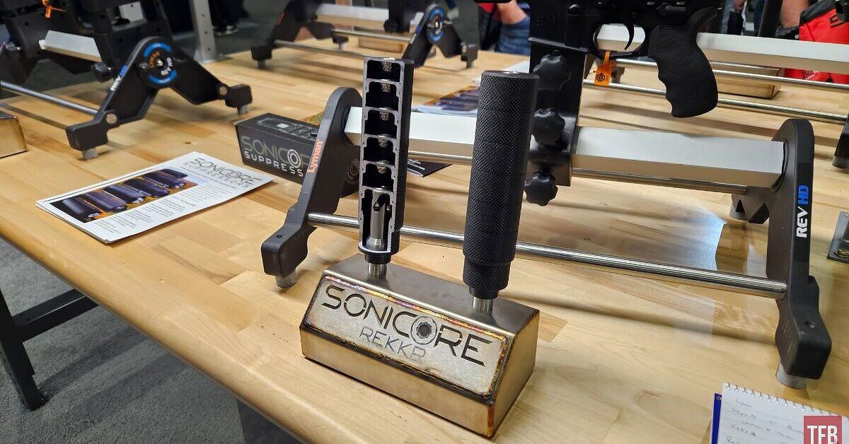 Assortment of new 2026 suppressors from Daniel Defense, Inland, Canik, and Lyman displayed on a shooting range table with rifles and pistols.
